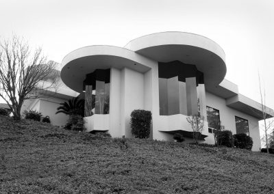 A custom home architecture that showcases faceted tall angled windows and a circular roof line