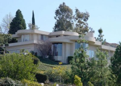 Multi-level home on sloping lot with significant trees with circular roof façade and a flat linear design